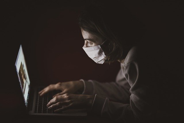 Woman wearing a mask using a laptop